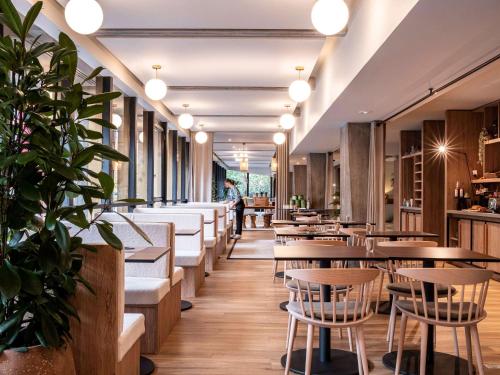 a restaurant with wooden tables and chairs and potted plants at Mercure Grenoble Centre Alpotel in Grenoble