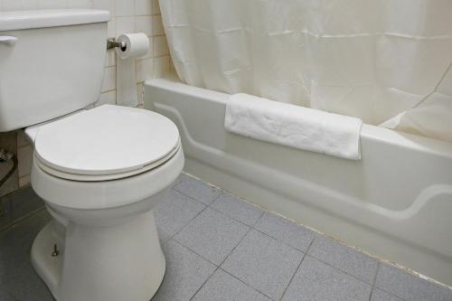 ein weißes Bad mit einem WC und einer Badewanne in der Unterkunft Hotel Petersburg VA I-95 & E Washington St in Petersburg