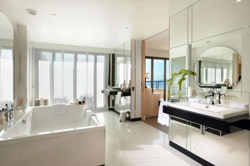 a bathroom with a tub and two sinks and a mirror at Hyatt Regency Nice Palais de la Méditerranée in Nice