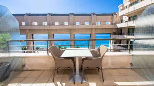 une table et des chaises devant une grande fenêtre dans l'établissement Hyatt Regency Nice Palais de la Méditerranée, à Nice