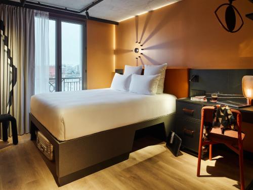 a hotel room with a bed and a desk with a window at Tribe Paris Saint Ouen in Saint-Ouen