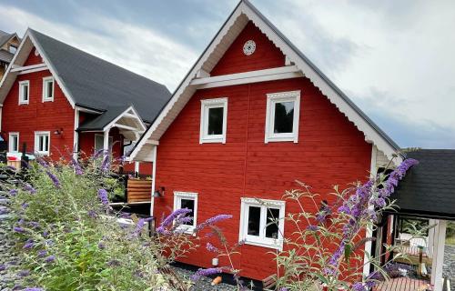 czerwony dom z białymi oknami i fioletowymi kwiatami w obiekcie Wioska w Sowich Sokolec w mieście Sokolec