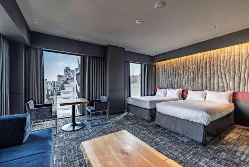 a hotel room with two beds and a couch at Wyndham Garden Sapporo Odori in Sapporo