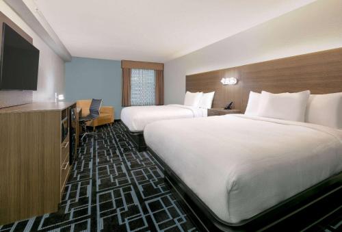 a hotel room with two beds and a flat screen tv at Baymont by Wyndham Chattanooga Eastridge in East Ridge