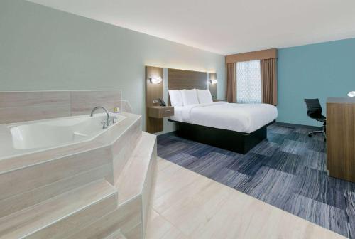a hotel room with a bed and a bath tub at Baymont by Wyndham Chattanooga Eastridge in East Ridge