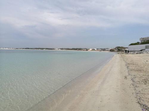a sandy beach with the ocean in the background at Villino Sabrina con piscina in Torre Lapillo