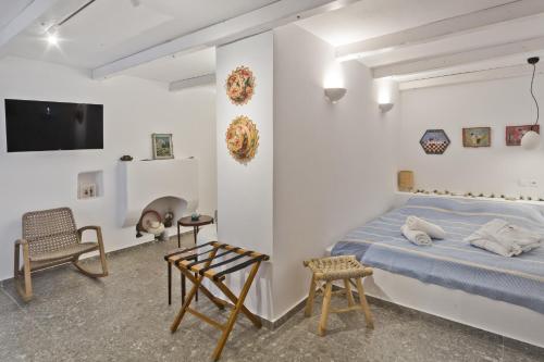 a white bedroom with a bed and a chair at Blé - Traditional Renovated Cottage in Afiartis