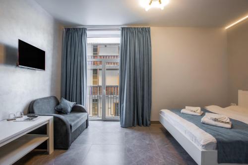 a hotel room with a bed and a chair and a window at Salut in Bukovel