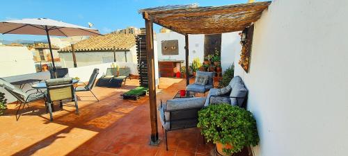 un patio con sillas, una mesa y una sombrilla en Atico ANAPER en Málaga