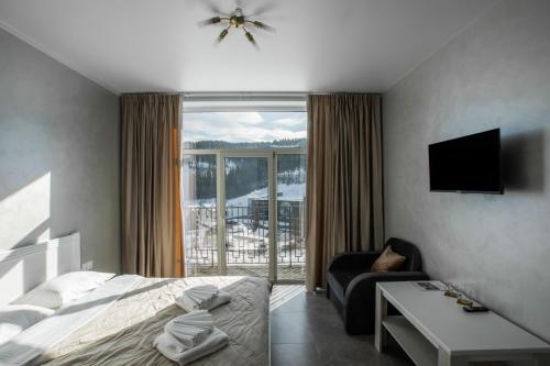 a bedroom with a bed and a couch and a window at Salut in Bukovel