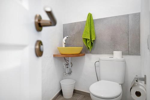 een badkamer met een wit toilet en een gele wastafel bij La Orilla del Volcán in Yaiza
