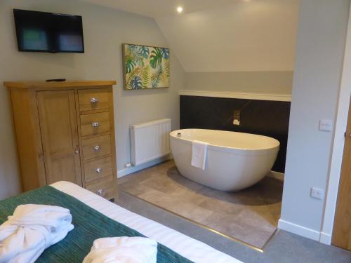 a bathroom with a large tub and a bed at Lord Galloway 37 with Hot Tub in Newton Stewart