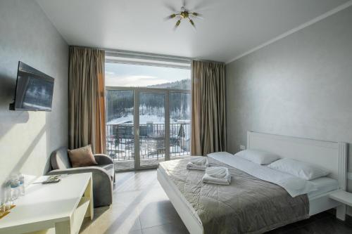 a bedroom with a bed and a chair and a large window at Salut in Bukovel