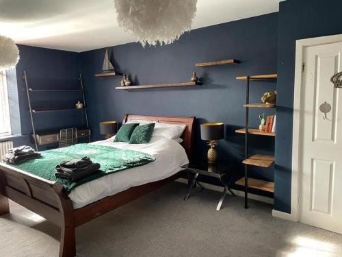 1 dormitorio con paredes azules, 1 cama y 1 mesa en The Beulah Apartments, en Leeds