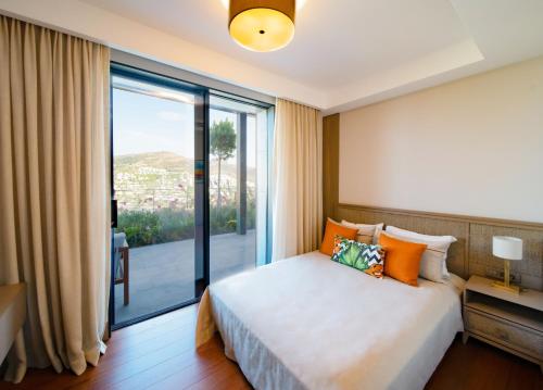 a bedroom with a bed and a large window at Mare Deluxe Residences & Villas in Gundogan