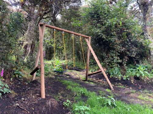 an empty swing set in a garden with trees at Mirador Bosque Gran Torino Neusa in Cogua