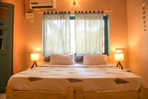 a bedroom with a large bed with two lamps at Coco Moon in Morjim