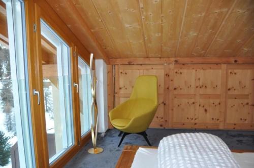 een gele stoel in een kamer met een raam bij Chesa Romana - Dach-Maisonette in Pontresina