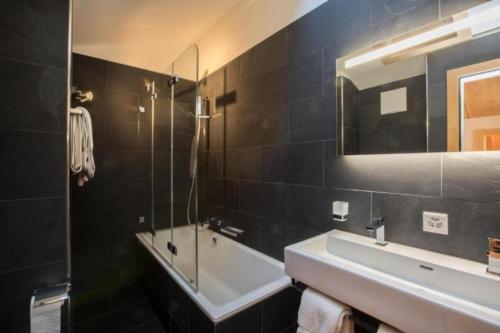 een badkamer met een wastafel, een bad en een spiegel bij Chesa Romana - Dach-Maisonette in Pontresina
