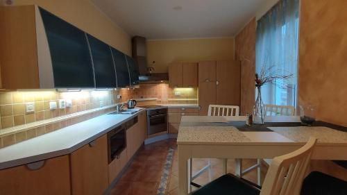 una cocina con armarios de madera y una isla de cocina con mesa en Apartmán v centru Jihlavy, en Jihlava