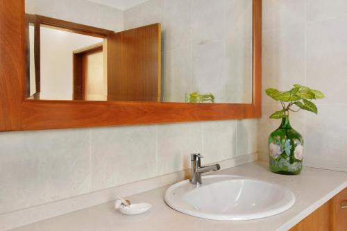 a bathroom sink with a mirror and a vase at Madeira Villa Liliana in Campanário