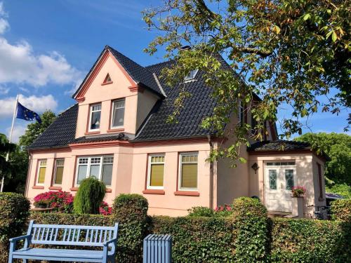 una casa rosa con un banco delante en Ferienwohnung Sonnensuite, en Wustrow