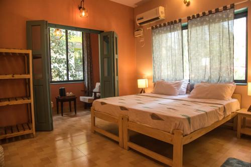 a bedroom with a large bed with orange walls and windows at Coco Moon in Morjim