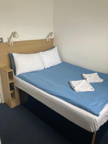 a bed with blue sheets and white pillows on it at Hostel Alma in Dover