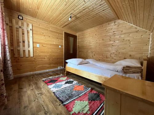 a bedroom with a bed in a wooden room at Cabana Sânziana in Gîrda de Sus