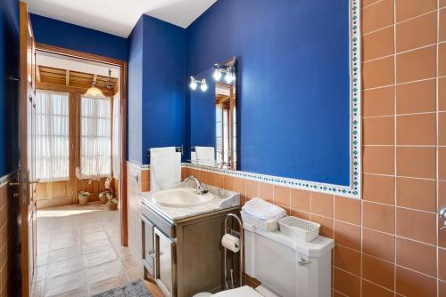 uma casa de banho com paredes azuis, um lavatório e um WC. em Casa 1700 Los Quemados em Los Quemados