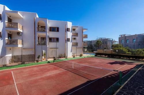 a tennis court in front of a building at Apartamentos Can Salas in Cala Figuera