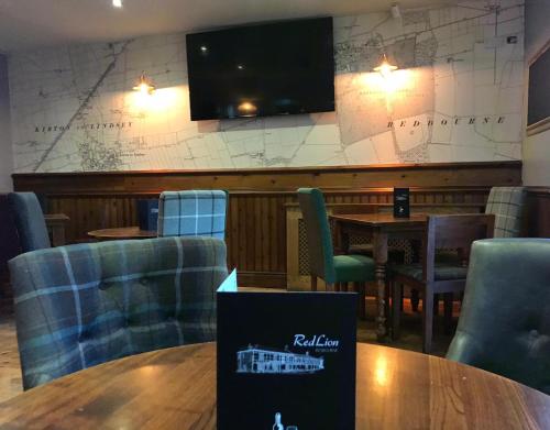 a restaurant with tables and chairs and a tv on the wall at Red Lion Coaching Inn in Redbourne