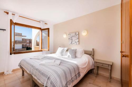 a bedroom with a bed with white sheets and a window at Apartamentos Can Salas in Cala Figuera