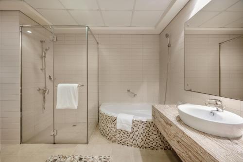 y baño con bañera, lavamanos y ducha. en Oaks Liwa Heights Hotel Suites en Dubái
