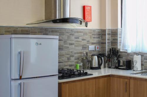 a kitchen with a white refrigerator and a stove at Highlands Suites Hotel Apartments in Nairobi