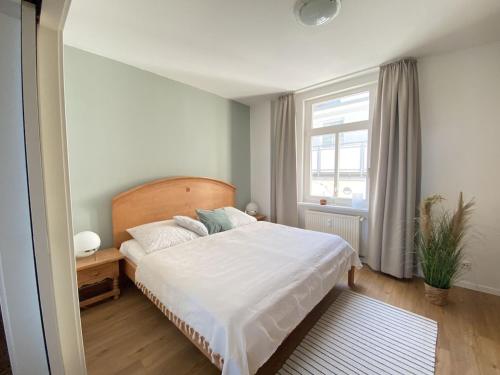 una camera da letto con un grande letto bianco e una finestra di Villa Seeblick Warnemünde - Fewo mit Meerblick und Balkon direkt am Strand für 2-4 Pers a Rostock