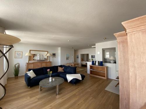 ein Wohnzimmer mit einem blauen Sofa und einem Tisch in der Unterkunft Villa Seeblick Warnemünde - Fewo mit Meerblick und Balkon direkt am Strand für 2-4 Pers in Rostock
