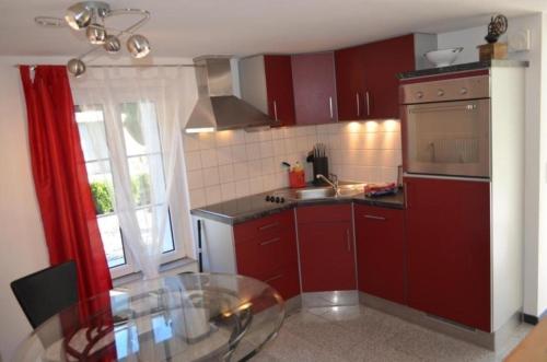 a kitchen with red cabinets and a glass table at mountain-panorama EG 2-Bettwohnung in Meiringen