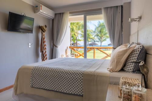 a bedroom with a bed and a view of the ocean at Paraíso dos Corais in Guarajuba
