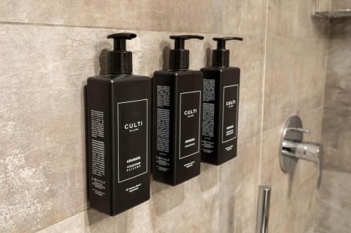 three black bottles on a wall in a bathroom at Hotel Regina in Milan