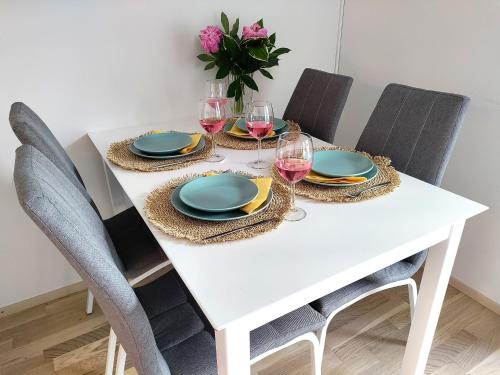 una mesa de comedor blanca con platos y copas de vino en Fully Equipped New Apartment With Free Parking, en Tampere