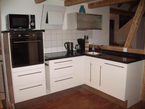 uma cozinha com armários brancos e um balcão preto em mountain-panorama DG 4-Bettwohnung em Meiringen