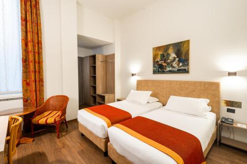 a hotel room with two beds and a chair at Hotel Regina in Milan