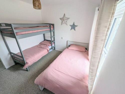 two bunk beds in a room with pink sheets at No.7 Perran View in St. Agnes