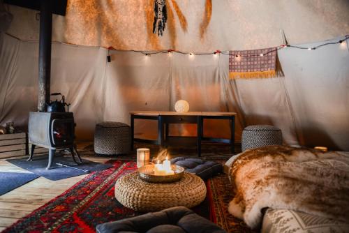 een woonkamer met een open haard en een tafel met een kaars bij Lapiland - off-grid yurts & tipis - the place to reconnect with nature 