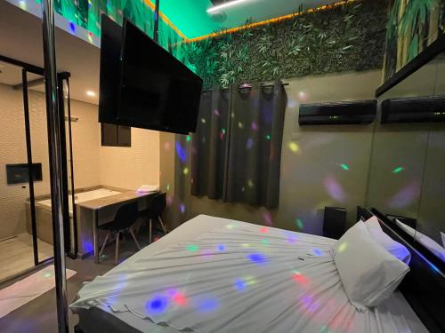 a bedroom with a bed and a television and a table at Lina Motel Tatuapé in Sao Paulo
