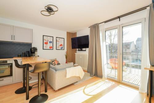 a living room with a couch and a kitchen with a balcony at LINDE3 - 10 Minuten in die Altstadt mit Balkon und Pegnitzblick in Nürnberg