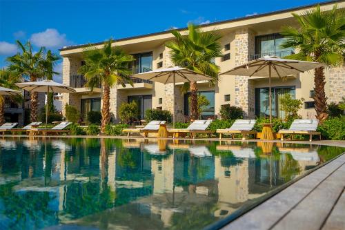 un complejo con una piscina con sillas y sombrillas en Palaia Hotel Datça, en Datça