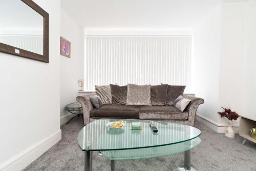 a living room with a couch and a glass table at Foxwood Stays in Leeds