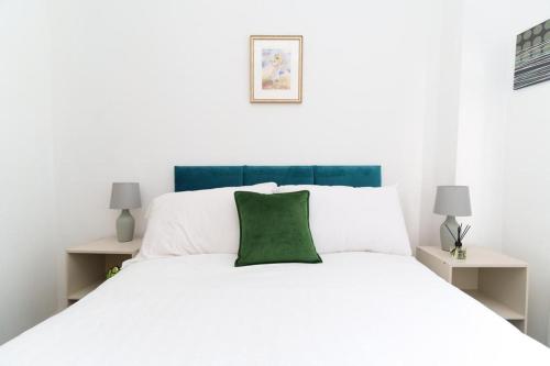 a white bed with a green pillow on top of it at Foxwood Stays in Leeds